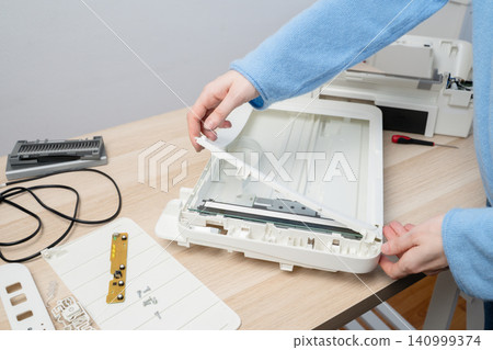 Hands Repairing Flatbed Scanner On Desk During Electronic Device Disassembly And Maintenance Hands Repairing Flatbed Scanner On Desk During Electronic Device Disassembly And Maintenance 140999374