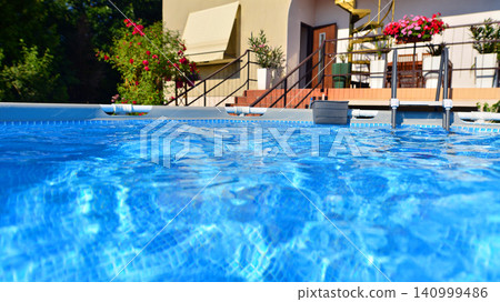 Large swimming pool set in the backyard next to the house. 140999486