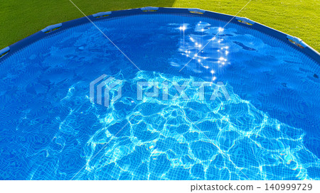Luxury swimming pool with blue water surrounded by green grass - relaxation and luxury lifestyle concept Luxury swimming pool with blue water surrounded by green grass - relaxation and luxury lifestyle concept 140999729