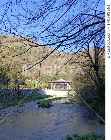 Beautiful lake view with mountains, houses, and clear blue sky during midday Beautiful lake view with mountains, houses, and clear blue sky during midday 140999961