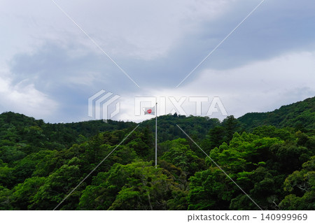 The Japanese flag (Hinomaru) flutters in the deep forests of Ise and the cloudy sky. The Japanese flag (Hinomaru) flutters in the deep forests of Ise and the cloudy sky. 140999969