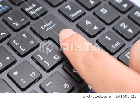 A person pressing keys on a computer keyboard 141000422