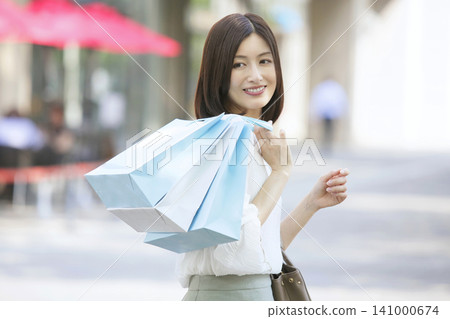 一位三十多歲的女子提著購物袋行走(購物圖片) 一位三十多歲的女子提著購物袋行走(購物圖片) 141000674