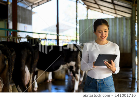 Young woman with digital tablet and cows on dairy farm 141001710