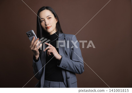 一個操作智能手機的年輕女子 一個操作智能手機的年輕女子 141001815