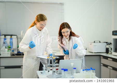 Two Excited Female Scientists Celebrating Research Breakthrough in Modern Laboratory 141001968