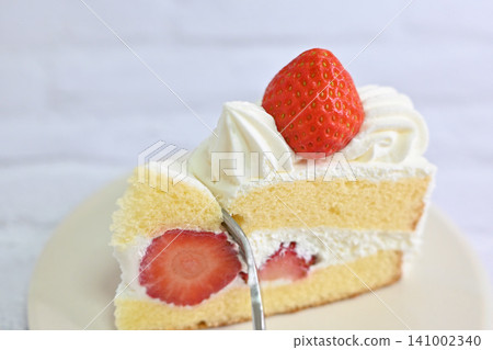 A photo of a strawberry shortcake on a white plate with a fork stuck in it. A photo of a strawberry shortcake on a white plate with a fork stuck in it. 141002340