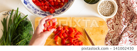 A person is chopping fresh tomatoes on a wooden board to prepare a salad. Nearby are bowls of other chopped vegetables and ingredients, all from local sources, showing a summer harvest, banner A person is chopping fresh tomatoes on a wooden board to prepare a salad. Nearby are bowls of other chopped vegetables and ingredients, all from local sources, showing a summer harvest, banner 141002430
