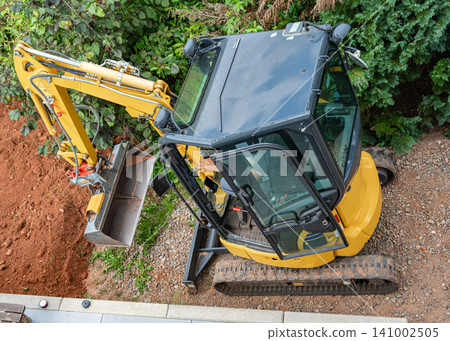 excavator actively working on outdoor construction site, surrounded by dirt pile and green vegetation, captured from top-down perspective, professional and clean environment, featuring both. excavator actively working on outdoor construction site, surrounded by dirt pile and green vegetation, captured from top-down perspective, professional and clean environment, featuring both. 141002505