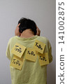 The back view of a person holding their head in their hands, overwhelmed by their to-do list. 141002875