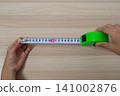 The hand extending the measuring tape to measure the length 141002876