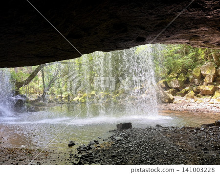 The scenery of Nabegataki waterfall in Minamioguni Town, Kumamoto Prefecture, surrounded by lush green trees and flowing from behind. The scenery of Nabegataki waterfall in Minamioguni Town, Kumamoto Prefecture, surrounded by lush green trees and flowing from behind. 141003228