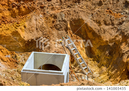 Workers are setting up concrete box in deep trench at construction site Workers are setting up concrete box in deep trench at construction site 141003435