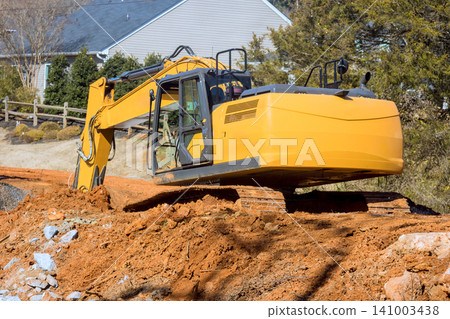 Heavy excavator machinery digs into soil at construction site near homes, dirt tools Heavy excavator machinery digs into soil at construction site near homes, dirt tools 141003438
