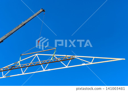 Crane lifts large wooden frame into air during construction work at building site Crane lifts large wooden frame into air during construction work at building site 141003481