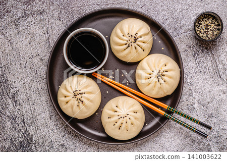 Steamed buns with savory filling served on a black plate Steamed buns with savory filling served on a black plate 141003622