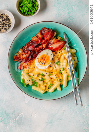 Korean street food - creamy rapokki served with bacon and egg. Korean street food - creamy rapokki served with bacon and egg. 141003641