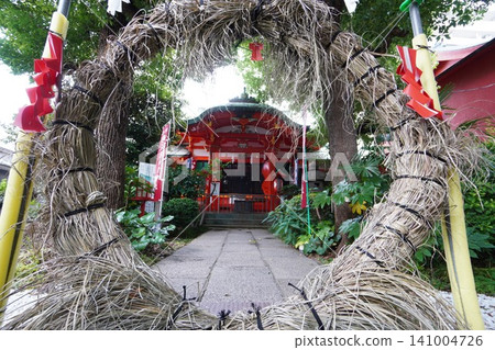 The vermilion shrine building of Oshima Inari Shrine as seen through a thatched ring. 141004726