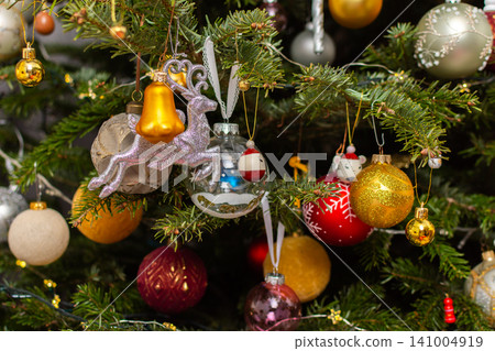A Christmas tree stands with many colorful ornaments hanging from its branches. Each ornament shows different shapes and colors, celebrating the festive season and bringing joy to the home A Christmas tree stands with many colorful ornaments hanging from its branches. Each ornament shows different shapes and colors, celebrating the festive season and bringing joy to the home 141004919