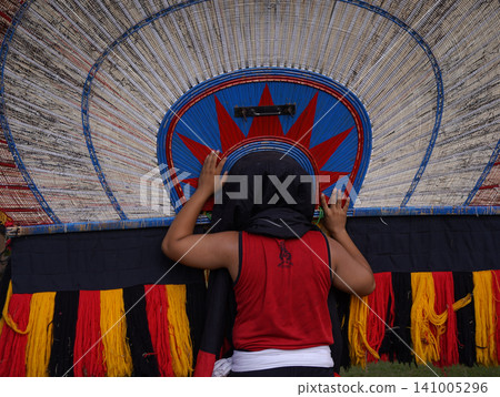 SURABAYA, INDONESIA - JULY 5, 2026: A performer wears the heavy Singo Barong tiger and peacock feather mask with 'Singo Sekar Budoyo' text during a traditional Reog Ponorogo cultural dance performance SURABAYA, INDONESIA - JULY 5, 2026: A performer wears the heavy Singo Barong tiger and peacock feather mask with 'Singo Sekar Budoyo' text during a traditional Reog Ponorogo cultural dance performance 141005296