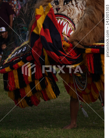SURABAYA, INDONESIA - JULY 5, 2026: A performer wears the heavy Singo Barong tiger and peacock feather mask with 'Singo Sekar Budoyo' text during a traditional Reog Ponorogo cultural dance performance SURABAYA, INDONESIA - JULY 5, 2026: A performer wears the heavy Singo Barong tiger and peacock feather mask with 'Singo Sekar Budoyo' text during a traditional Reog Ponorogo cultural dance performance 141005303