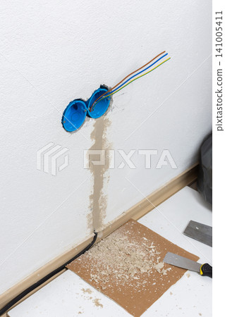 Apartment wall preparation for electrical outlets includes blue conduit boxes and exposed colored wires Apartment wall preparation for electrical outlets includes blue conduit boxes and exposed colored wires 141005411