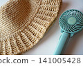 Using a portable fan and a straw hat to cope with the heat. 141005428