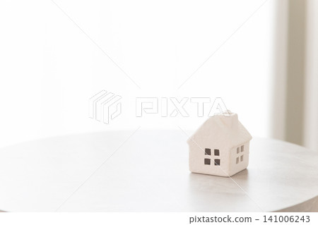 A small white house on a table, with white space (copy space) that can be used for real estate and housing-related concepts. A small white house on a table, with white space (copy space) that can be used for real estate and housing-related concepts. 141006243