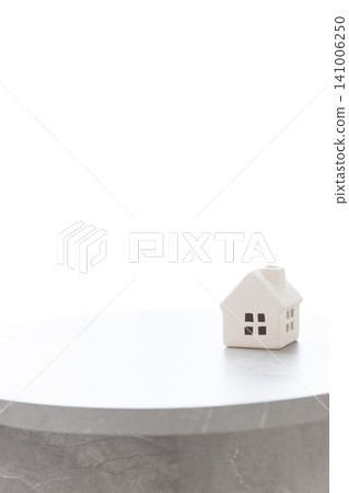 A small white house on a table, with white space (copy space) that can be used for real estate and housing-related concepts. 141006250