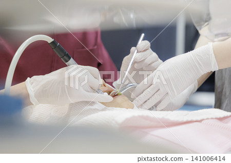 A scene from a dental treatment setting: a doctor and an assistant performing a procedure. A scene from a dental treatment setting: a doctor and an assistant performing a procedure. 141006414