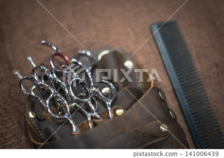 A complete set of hairdressing scissors and comb that fits in a leather scissor case. A complete set of hairdressing scissors and comb that fits in a leather scissor case. 141006439