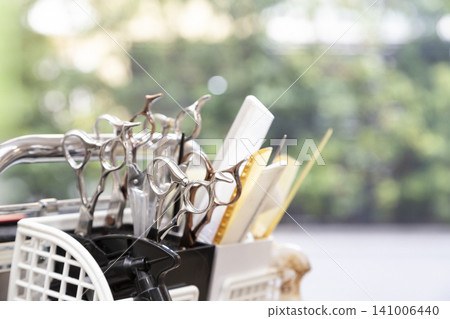 A still-life photograph of a hairdresser's scissors and combs against a green bokeh background. A still-life photograph of a hairdresser's scissors and combs against a green bokeh background. 141006440
