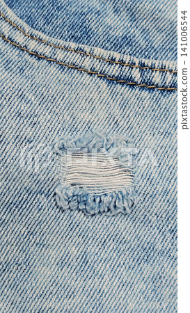 Close-up of stonewashed denim jeans with hole Close-up of stonewashed denim jeans with hole 141006544