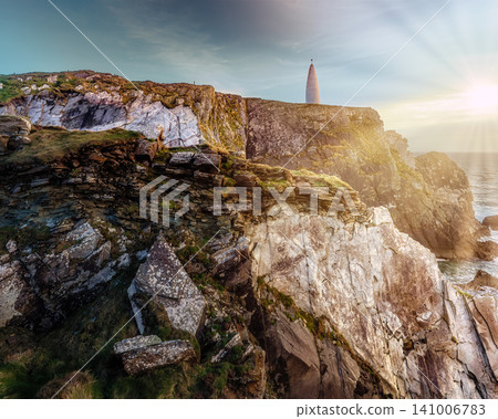 A white, cone-shaped marker stands on a rugged cliff overlooking the ocean. A white, cone-shaped marker stands on a rugged cliff overlooking the ocean. 141006783