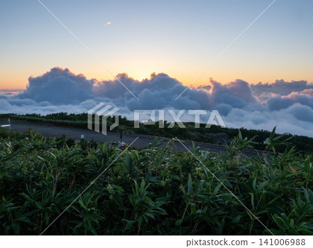 A gradient of sunset sinking into a sea of clouds 141006988