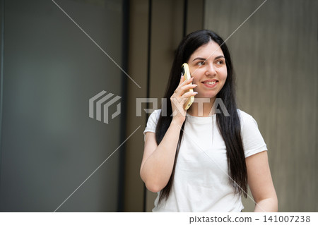 Young woman smiling while making a business call on smartphone in an urban environment. Professional mobile communication and customer support service Young woman smiling while making a business call on smartphone in an urban environment. Professional mobile communication and customer support service 141007238