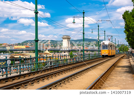 Budapest, Hungary: The famous yellow trams (streetcars) running along the Danube River and the Széchenyi Chain Bridge. Budapest, Hungary: The famous yellow trams (streetcars) running along the Danube River and the Széchenyi Chain Bridge. 141007319
