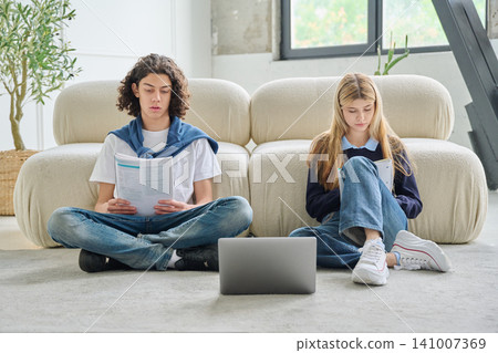 Two teenage students studying on floor with laptop 141007369