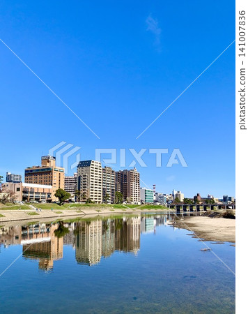 The cityscape on the right bank downstream of Tonobashi Bridge, bathed in the clear blue autumn sky, is reflected in the water's surface. (Otogawa River Green Space (from the Submersible Bridge)/Okazaki City, Aichi Prefecture) The cityscape on the right bank downstream of Tonobashi Bridge, bathed in the clear blue autumn sky, is reflected in the water's surface. (Otogawa River Green Space (from the Submersible Bridge)/Okazaki City, Aichi Prefecture) 141007836