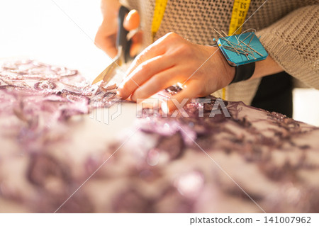 Tailor hands cutting lace fabric for new design 141007962