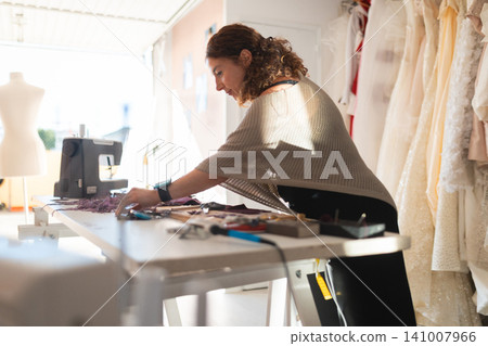Female tailor creating bridal gown in workshop atelier Female tailor creating bridal gown in workshop atelier 141007966