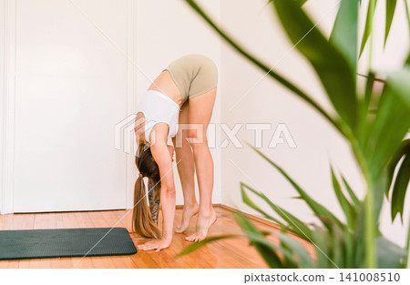 Woman Doing Standing Forward Fold Workout Woman Doing Standing Forward Fold Workout 141008510