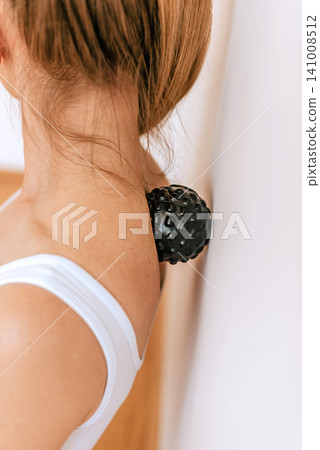Woman Using Massage Ball on Neck Against Wall Woman Using Massage Ball on Neck Against Wall 141008512