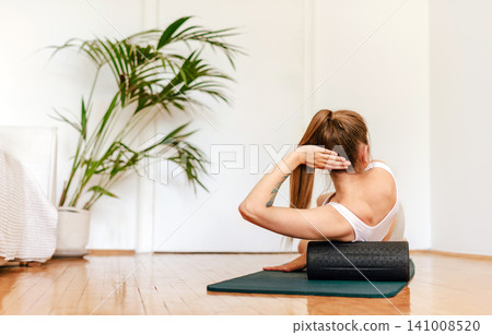 Woman Using Roller for Back Massage Recovery At Home 141008520