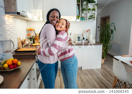Mother and daughter embracing with love in modern kitchen Mother and daughter embracing with love in modern kitchen 141008545