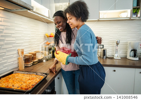 Mother and daughter baking pizza together in kitchen at home Mother and daughter baking pizza together in kitchen at home 141008546