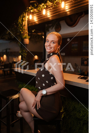 Young adult woman smiling at bar during evening nightlife Young adult woman smiling at bar during evening nightlife 141008691