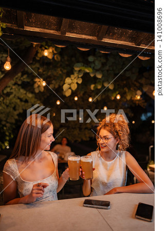 Women friends making toast with beer at outdoor bar Women friends making toast with beer at outdoor bar 141008696