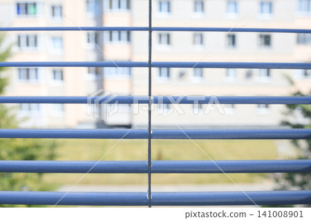 Dusty blue window blinds front view, dirty metal jalousie slats close up with blurred multi story building backdrop Dusty blue window blinds front view, dirty metal jalousie slats close up with blurred multi story building backdrop 141008901