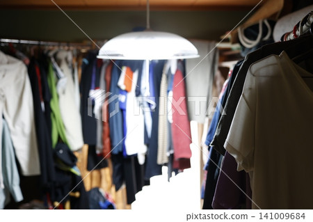 A messy, untidy room. A closet overflowing with clothes. Organizing clothes. A messy, untidy room. A closet overflowing with clothes. Organizing clothes. 141009684
